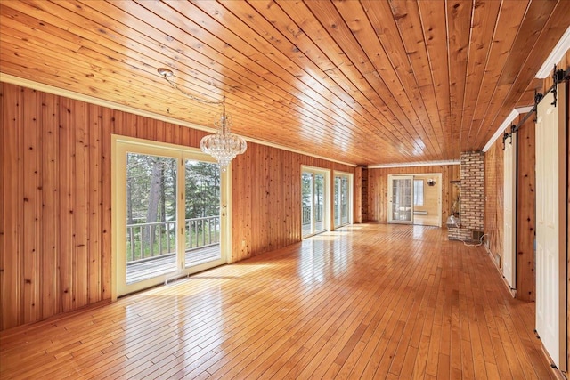 unfurnished living room with crown molding, light hardwood / wood-style flooring, and a chandelier