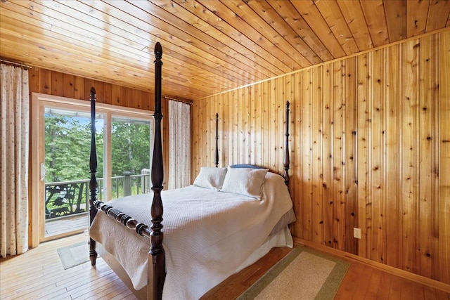 bedroom featuring access to exterior, wooden walls, hardwood / wood-style floors, and wooden ceiling