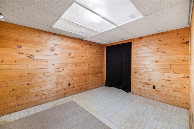 empty room with a drop ceiling and wooden walls