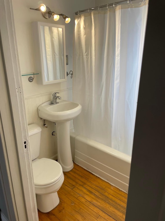 bathroom with hardwood / wood-style flooring, shower / bath combo, and toilet