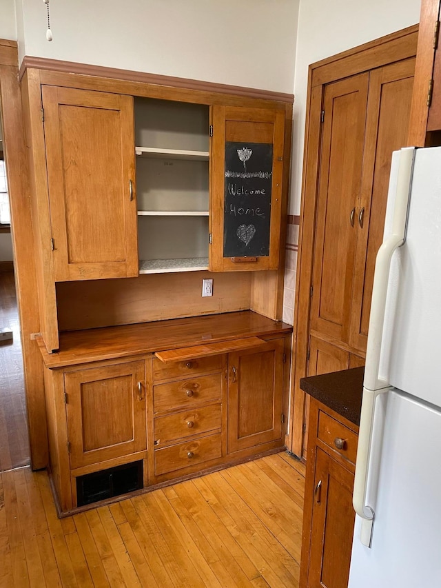 interior space featuring white refrigerator, dark stone counters, and light hardwood / wood-style flooring