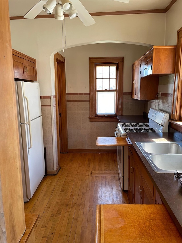 kitchen featuring sink, white appliances, light hardwood / wood-style flooring, ornamental molding, and ceiling fan