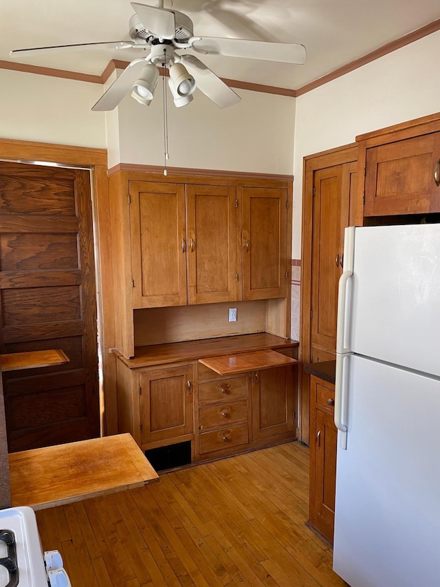 kitchen with crown molding, light hardwood / wood-style flooring, ceiling fan, and white refrigerator