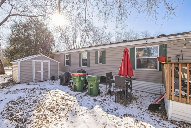 snow covered house featuring a storage unit