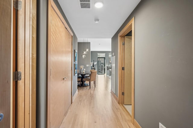 hall featuring light wood-style flooring and visible vents