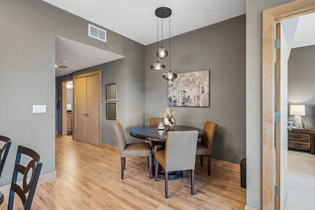 dining space featuring light wood-style floors, visible vents, and baseboards