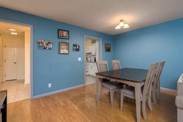 dining space with a textured ceiling and light wood-type flooring