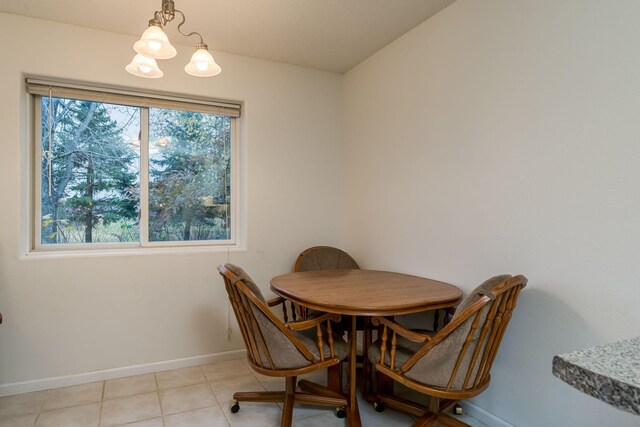 dining area with light tile patterned floors, baseboards, and an inviting chandelier