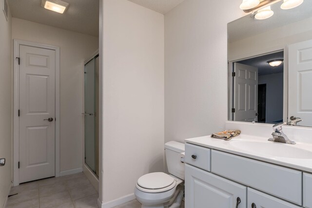 bathroom with tile patterned flooring, a shower stall, toilet, and vanity