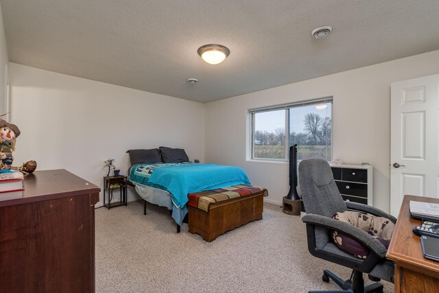 bedroom with visible vents, light carpet, a textured ceiling, and baseboards