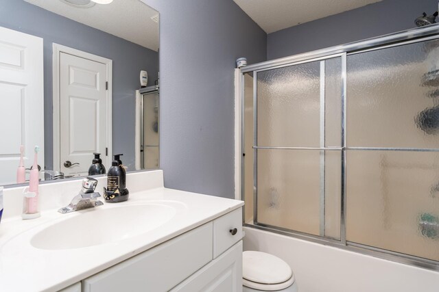 full bathroom with vanity, enclosed tub / shower combo, and toilet