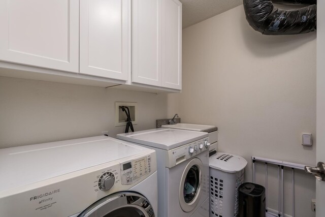 washroom featuring cabinets and washer and clothes dryer