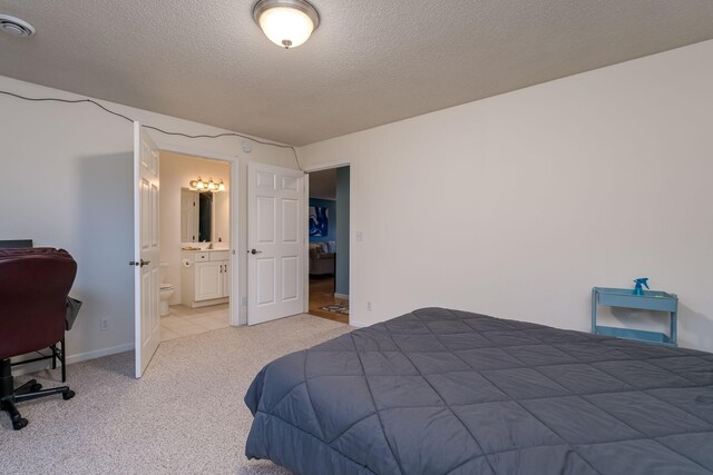 bedroom with ensuite bathroom, carpet floors, and a textured ceiling