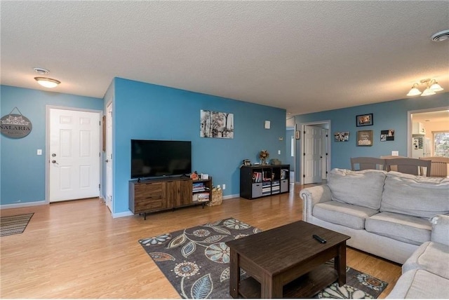 living room featuring baseboards, a textured ceiling, and wood finished floors