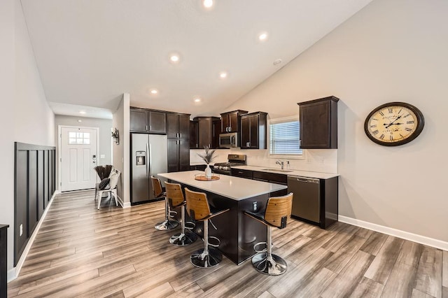 kitchen with a center island, stainless steel appliances, light countertops, a sink, and a kitchen breakfast bar