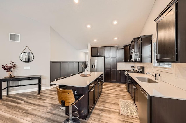 kitchen featuring a sink, a kitchen island, visible vents, light countertops, and appliances with stainless steel finishes