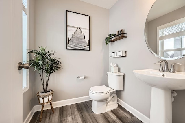 half bathroom featuring toilet, baseboards, and wood finished floors