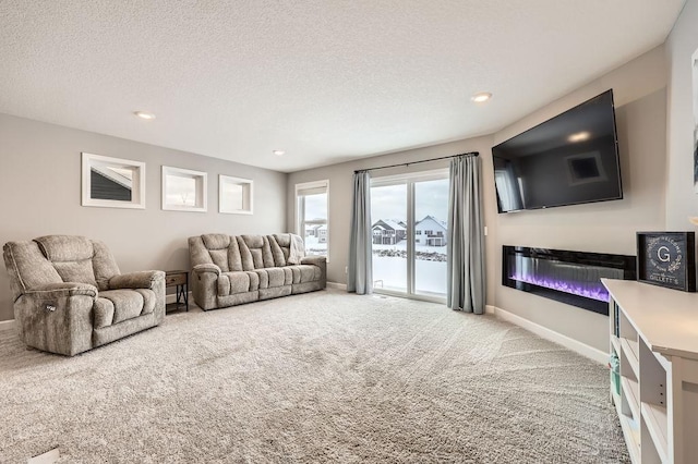 living area featuring a textured ceiling, recessed lighting, carpet floors, baseboards, and a glass covered fireplace