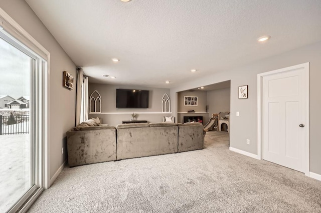 unfurnished living room featuring recessed lighting, carpet flooring, a textured ceiling, a lit fireplace, and baseboards