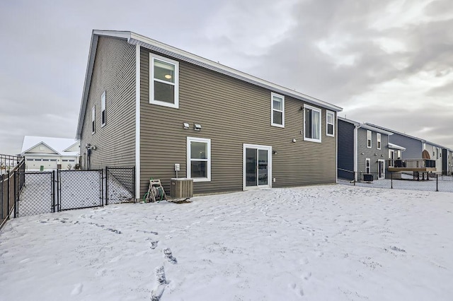 snow covered rear of property featuring central AC unit and fence