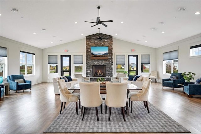 dining area with vaulted ceiling, a large fireplace, plenty of natural light, and light wood-style flooring