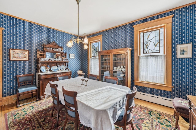 dining room with hardwood / wood-style floors, a baseboard radiator, and a chandelier