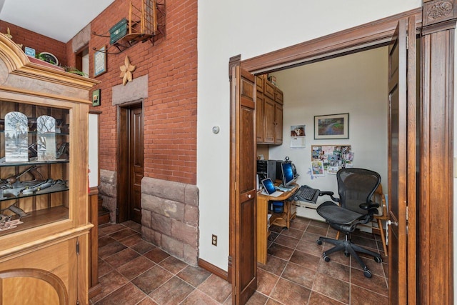 office with brick wall, built in desk, and a high ceiling