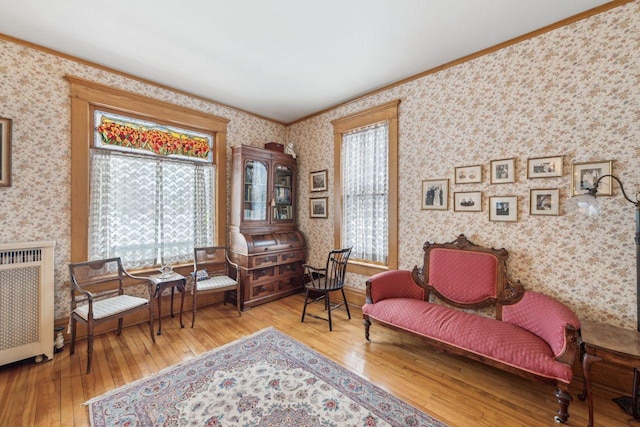 living area with radiator, crown molding, and light hardwood / wood-style floors