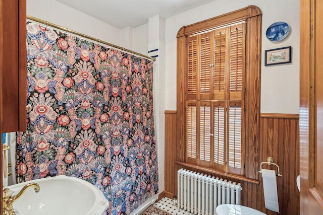 bathroom with radiator, sink, and wood walls
