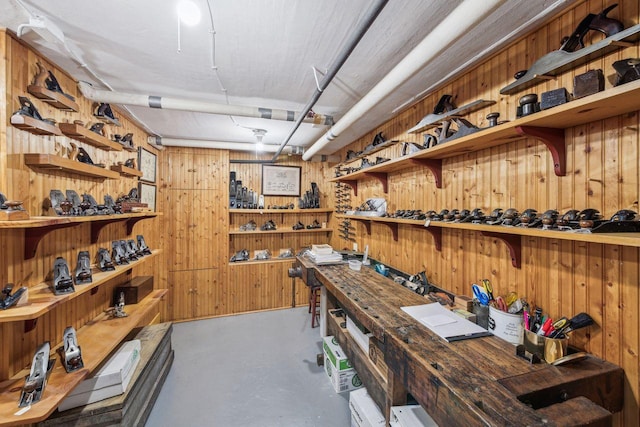 wine room featuring concrete flooring, wooden walls, and a workshop area