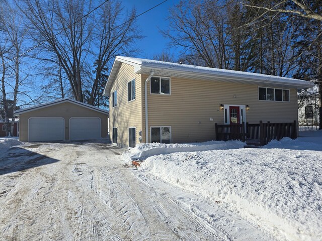 view of snowy exterior with an outdoor structure and a detached garage