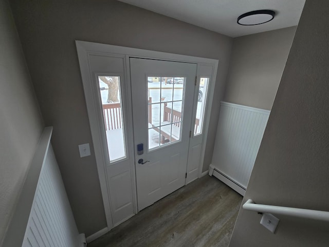 doorway to outside with wainscoting, baseboard heating, and wood finished floors