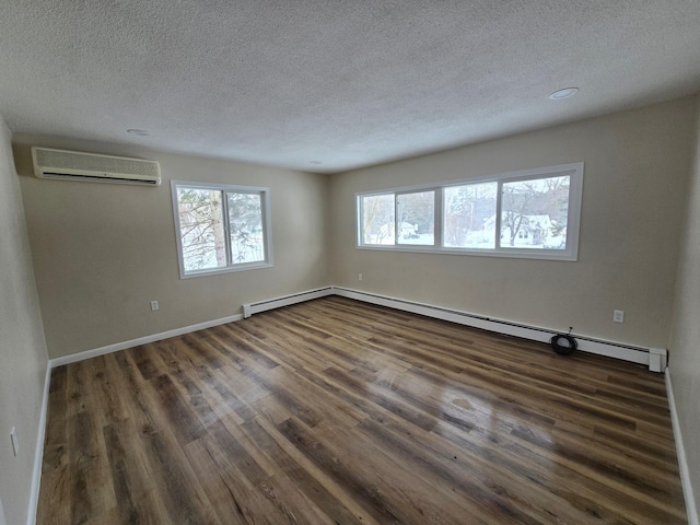 spare room featuring baseboards, dark wood finished floors, a wall unit AC, a textured ceiling, and a baseboard heating unit