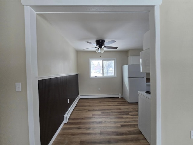 kitchen featuring a baseboard radiator, dark wood finished floors, freestanding refrigerator, and white cabinetry