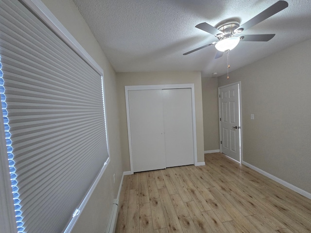 unfurnished bedroom featuring a textured ceiling, wood finished floors, a ceiling fan, baseboards, and a closet