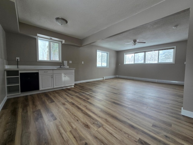 bar with a textured ceiling, wood finished floors, a sink, and baseboards