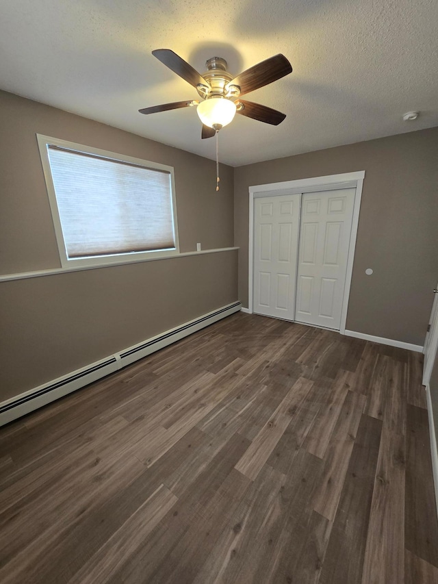 unfurnished bedroom featuring ceiling fan, wood finished floors, baseboard heating, a textured ceiling, and a closet