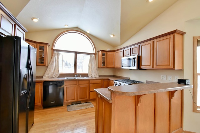 kitchen featuring vaulted ceiling, black appliances, sink, a kitchen bar, and kitchen peninsula