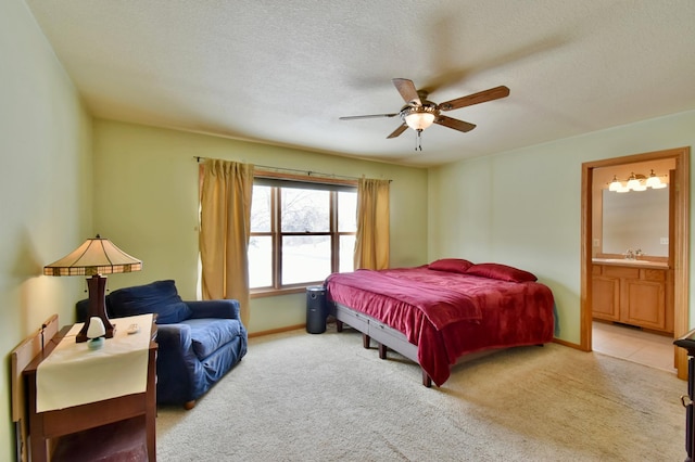 bedroom featuring connected bathroom, light colored carpet, a textured ceiling, and ceiling fan