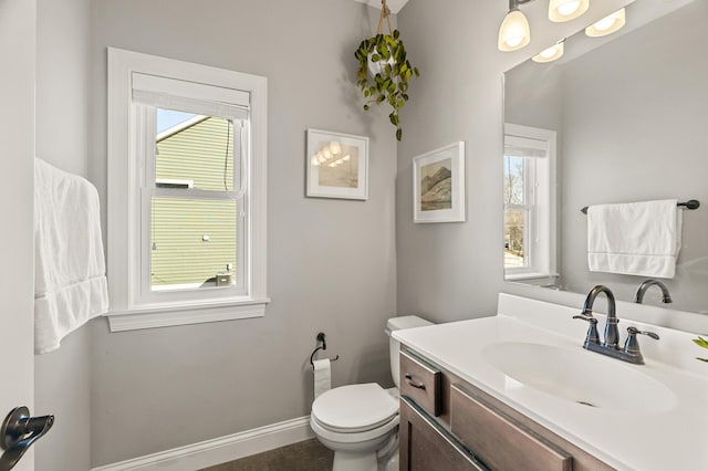 half bathroom with vanity, toilet, and baseboards