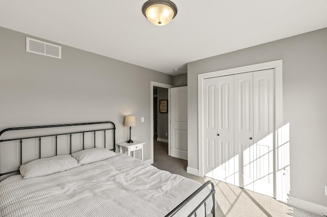 carpeted bedroom with a closet, visible vents, and baseboards