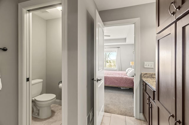 ensuite bathroom featuring vanity, baseboards, tile patterned floors, toilet, and connected bathroom