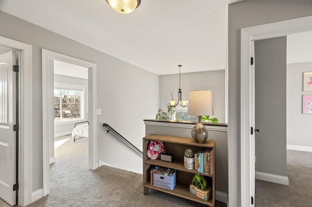 corridor with an upstairs landing, carpet flooring, and baseboards