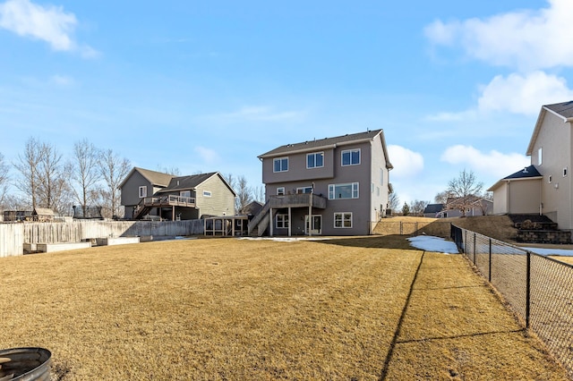 rear view of property with a fenced backyard, a deck, and a yard