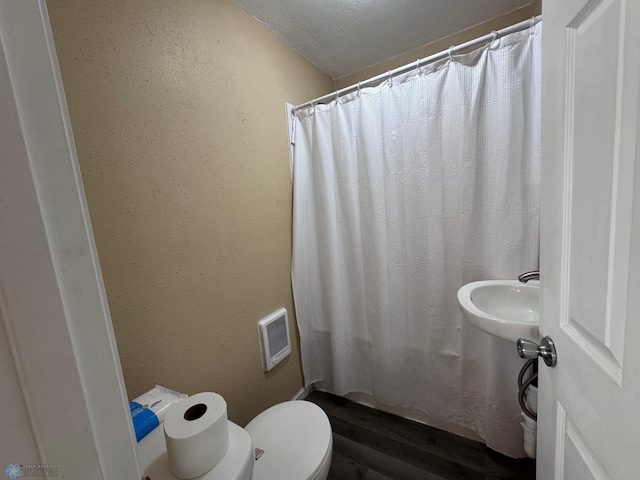 bathroom with a textured ceiling, toilet, and a shower with shower curtain