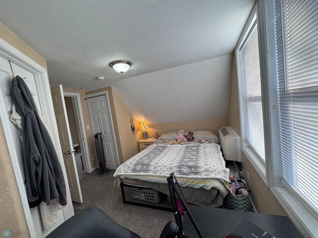 bedroom featuring lofted ceiling, carpet floors, a wall mounted AC, and a textured ceiling