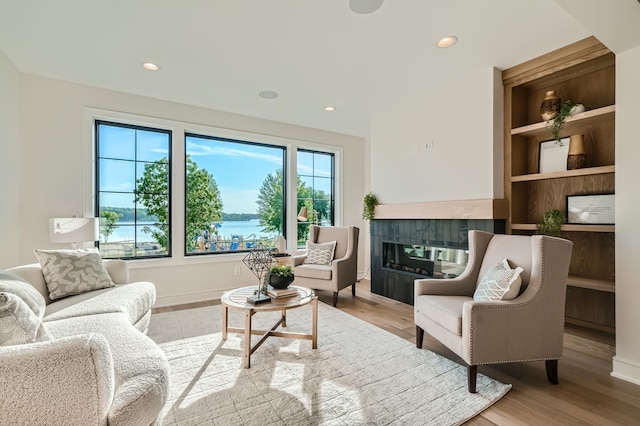 sitting room featuring built in shelves, light hardwood / wood-style floors, and a water view