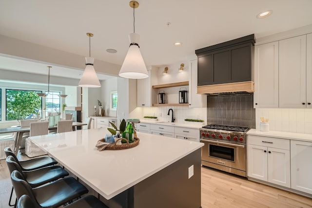 kitchen featuring white cabinetry, luxury stove, decorative light fixtures, and a center island