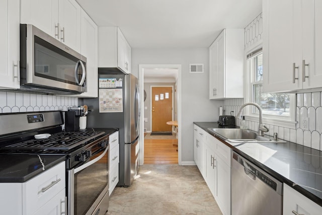 kitchen featuring sink, white cabinets, stainless steel appliances, and decorative backsplash