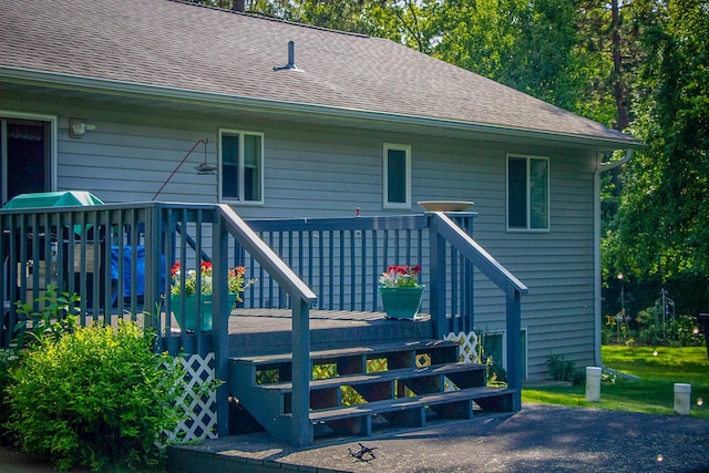 rear view of property featuring roof with shingles and a wooden deck